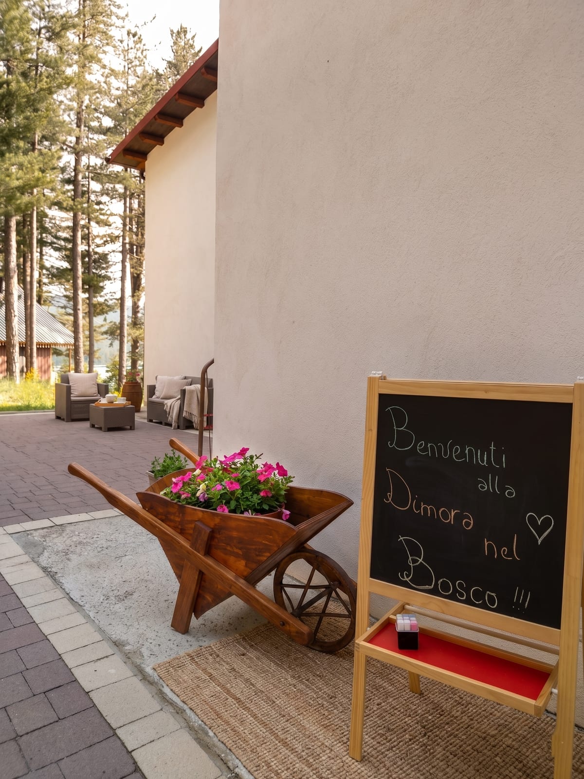 Welcome chalkboard and flower-filled wheelbarrow at the entrance of Dimora nel Bosco, surrounded by the Sila pine woods